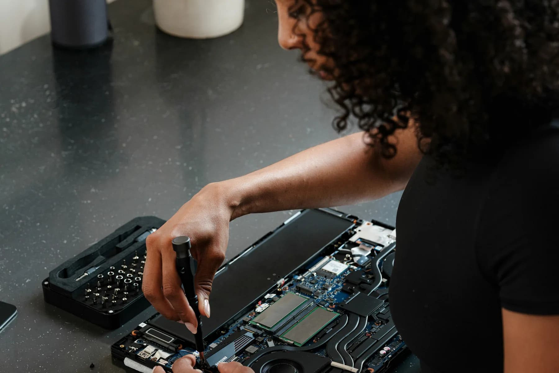 Electronics technician working on an open computer at a repair bench