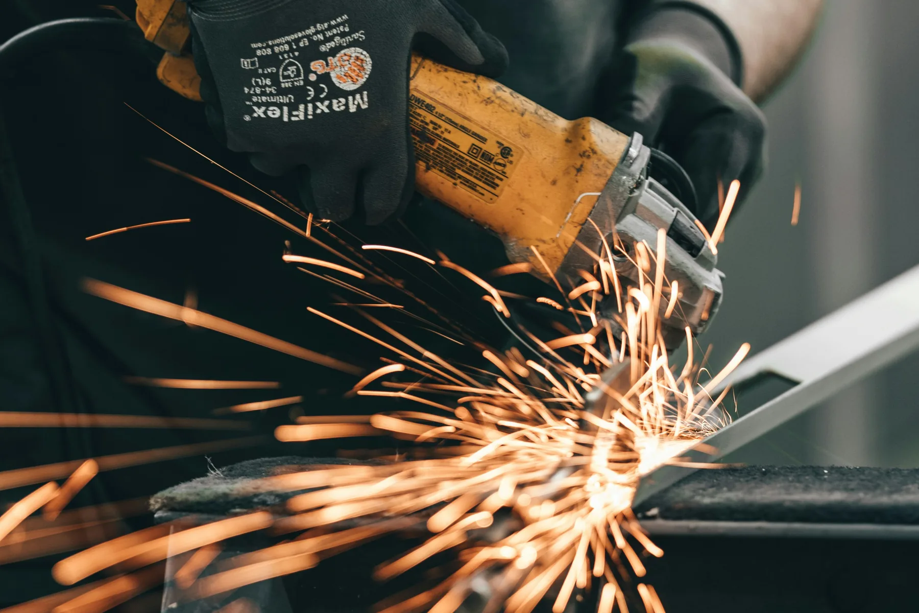 Fabrication worker using an angle grinder on a metal component