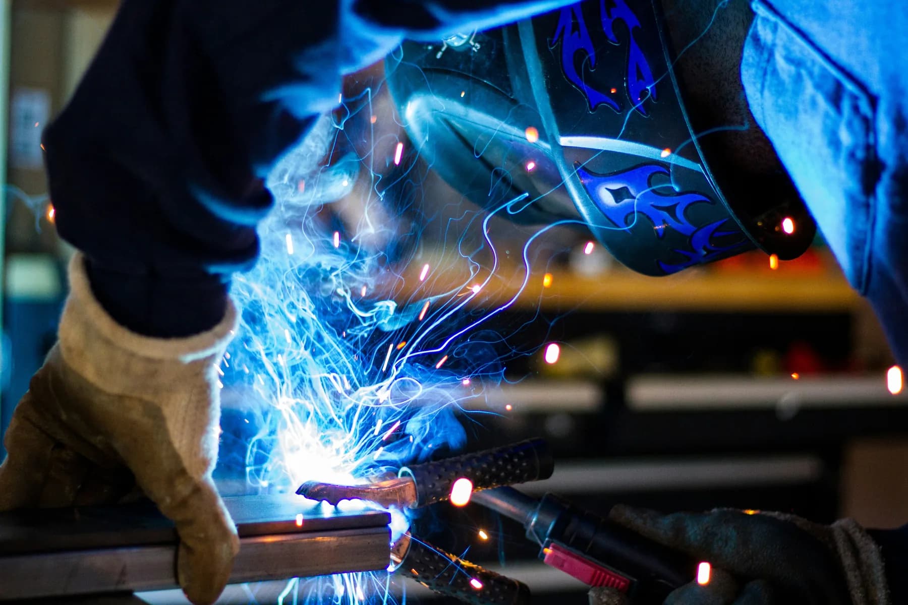 Welder joining metal components inside a fabrication workshop