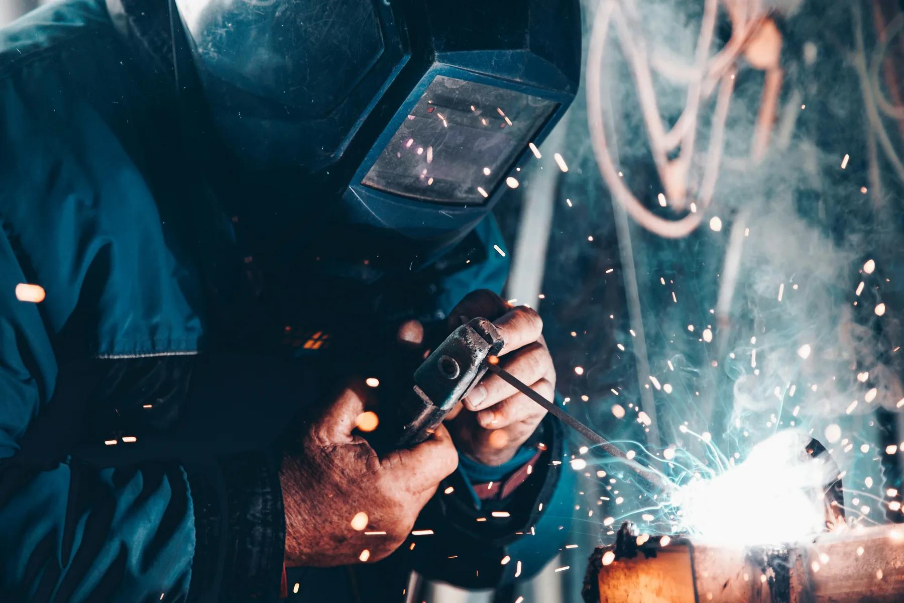 Welder fabricating metal components inside an industrial shop